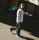 Person wearing a white sweatshirt and gray beanie walking on a street.