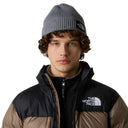 Person wearing a The North Face beanie and jacket on a gray background