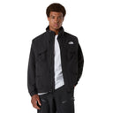 Person wearing a black jacket with a brand logo on a gray background