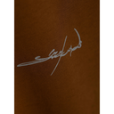 Brown fabric with a signature-style logo embroidered on it