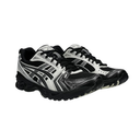 A pair of ASICS athletic sneakers in black and white, featuring the brand's signature stripe design on the side, black laces, and a black sole, set against a plain white background.