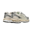 A pair of vintage Asics running shoes in light gray, beige, and white, featuring the classic Gel technology midsole and metallic side stripes, shown against a plain white background.