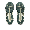 A pair of athletic shoes shown from the bottom, displaying their dark green and off-white textured rubber soles against a plain white background.