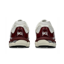 A pair of Nike Air Max 90 sneakers shown from the back, featuring a glossy burgundy heel counter with the white 'GEL' logo, white mesh side panels, and a chunky off-white midsole.