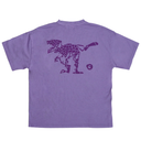 A purple short-sleeve t-shirt shown from the back, featuring a dark purple graphic of a dinosaur kicking a soccer ball on a solid white background.