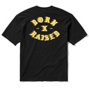 A black short-sleeve t-shirt shown from the back, featuring a large textured gold graphic on the upper back that reads 'BORN X RAISED' in a stylized font.