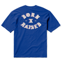 A royal blue short-sleeve t-shirt shown from the back, featuring a large, stylized white and light pink graphic text that reads 'BORN X RAISED' across the upper back.