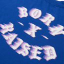 A close-up of a royal blue t-shirt featuring a stylized graphic print in white and light purple that reads 'BORN BRED'.