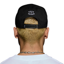 Back view of a man wearing a black baseball cap with a white embroidered logo on the back, shown against a plain white background.