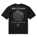 A black short-sleeve t-shirt with a white graphic print on the back, featuring the text 'BORN X RAISED', a detailed crest illustration, and 'PARANOIA' in large letters.