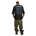 A man shown from the back wearing a black oversized jersey with 'PARANOIA' and the number '96' in white outlined lettering, paired with olive green cargo pants, against a plain white background.