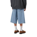 Person wearing blue denim shorts, a dark jacket, white socks, and brown shoes on a white background