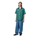 Person wearing a green shirt and blue jeans on a white background