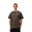 A man wearing an oversized olive green t-shirt with a small gold Carhartt logo on the left chest, paired with black pants and a silver chain necklace, set against a plain white background.