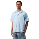 Man wearing a light blue short-sleeve shirt and plaid pants on a white background
