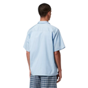 Person wearing a light blue shirt and plaid pants on a white background