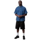 Person wearing a blue denim shirt and black shorts on a white background