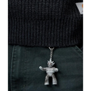 A silver Carhartt robot keychain hanging from a black ribbed knit sweater and dark green pants.