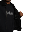 A close-up of a person wearing a black Dickies jacket over a black t-shirt with a white outlined 'Dickies' logo on the chest, holding the jacket open against a plain white background.