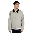 A man wearing a light beige Dickies work jacket with a black corduroy collar, standing against a solid white background.