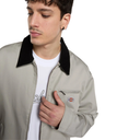 A man wearing a light beige Dickies work jacket with a black collar, layered over a white t-shirt, photographed against a solid white background.