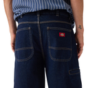 Person wearing blue jeans with a Dickies logo on a white background