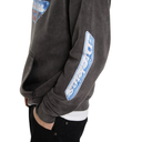 A close-up side view of a person wearing a dark charcoal gray sweatshirt with a large blue and white 'Dickies' logo patch on the sleeve and a matching patch on the upper chest, paired with black pants.
