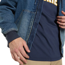 Close-up of a person wearing a blue denim zip-up jacket over a navy blue t-shirt with yellow lettering, paired with khaki pants.