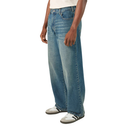 A person wearing light blue wide-leg denim jeans with a faded wash, paired with white sneakers, shown from the waist down on a plain white background.