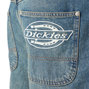Close-up of a blue denim jeans pocket showing the white embroidered Dickies logo patch on the back pocket.