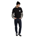 A man modeling a black long-sleeve collared shirt with a gray and black striped pattern on the sleeves, paired with dark blue jeans, a black beanie, and black sneakers, against a plain white background.