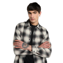 A man wearing a black, gray, and white plaid button-down shirt over a black t-shirt, posed with his arms crossed against a solid white background.