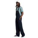 Person wearing dark denim overalls and a light blue shirt on a white background