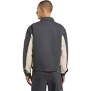 Person wearing a dark gray jacket with beige sleeves on a white background