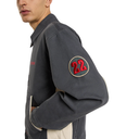 Person wearing a dark gray jacket with a red and gold patch on the sleeve featuring the number 22.