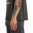 Person wearing a black t-shirt with visible tattoos on arms and hands.