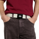 A close-up of a person wearing a Dickies work belt with a black logo plate and cream webbing, paired with a maroon t-shirt and dark gray jeans against a white background.