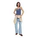 Woman wearing a blue tank top and light blue jeans with a beige apron on a white background