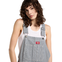 A model with curly brown hair wearing Dickies blue and white striped bib overalls over a white tank top, photographed against a solid white background.