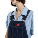 Person wearing blue denim overalls with a visible Dickies logo on a white background