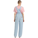 Person wearing light blue denim overalls and a pink shirt on a white background