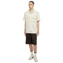 Man wearing a beige short-sleeve shirt and brown shorts on a white background