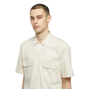 Man wearing a beige short-sleeve shirt on a white background