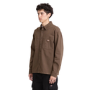 A man wearing a brown long-sleeve button-up shirt with two chest pockets, paired with black cargo pants, photographed against a solid white background.