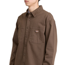 A person wearing a brown long-sleeve button-up shirt with two chest pockets and a small Dickies logo patch on the left chest pocket, photographed against a plain light background.