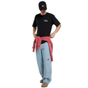Person wearing a black t-shirt, light blue jeans, and a red jacket over their shoulder on a white background