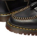 Close-up of black leather boots with yellow stitching on a white background