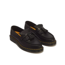 A pair of black leather tassel loafers with yellow contrast stitching and black soles, photographed on a clean white background.
