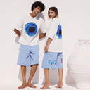 Two people wearing matching white oversized shirts with blue circular designs and light blue shorts on a white background.