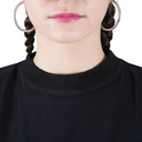 Person wearing a black sweater with hoop earrings and braided hair on a white background